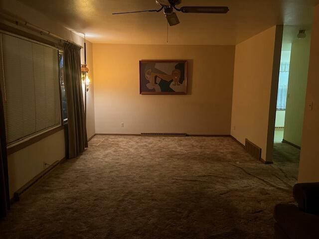 unfurnished room with carpet floors, baseboards, visible vents, and a ceiling fan