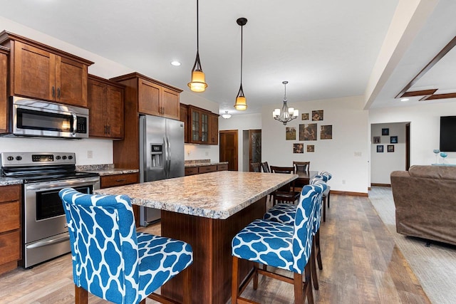 kitchen featuring a breakfast bar area, wood finished floors, open floor plan, appliances with stainless steel finishes, and a center island