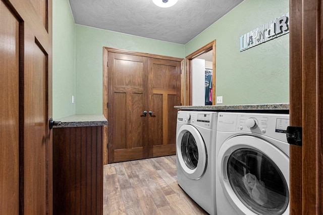 laundry area featuring light wood-style floors, laundry area, a textured ceiling, and separate washer and dryer