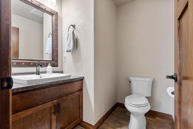 bathroom with toilet, baseboards, wood finished floors, and vanity