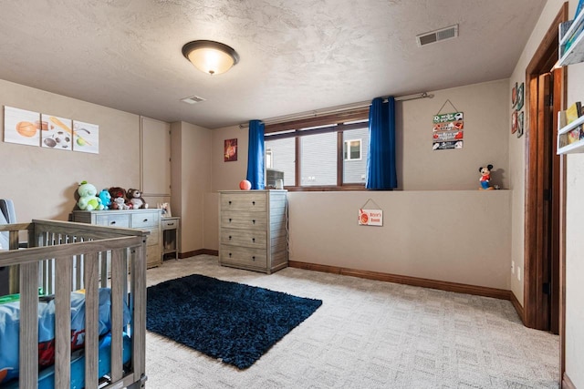 carpeted bedroom featuring baseboards, visible vents, and a textured ceiling