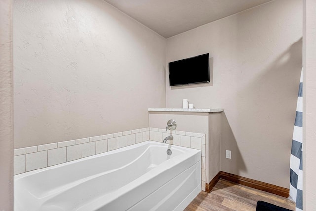 full bathroom with a garden tub, baseboards, and wood finished floors