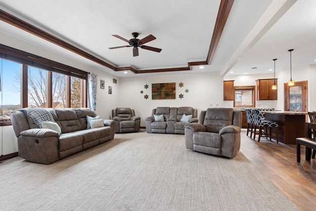 living area with a tray ceiling, crown molding, recessed lighting, a ceiling fan, and wood finished floors