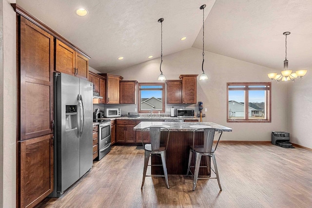 kitchen with lofted ceiling, a kitchen island, a breakfast bar area, stainless steel appliances, and a sink