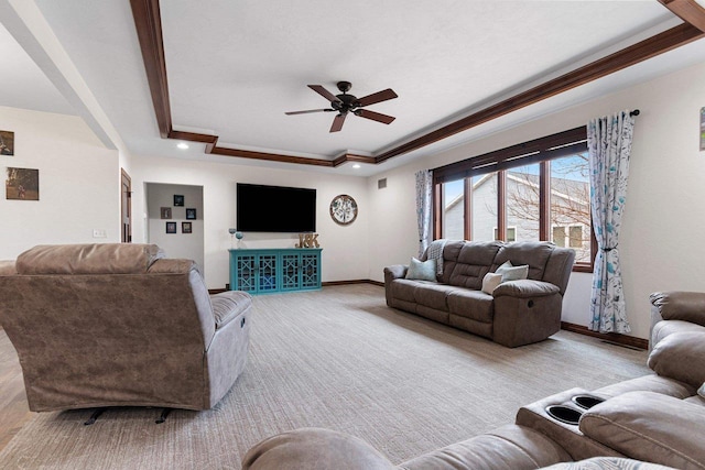 living area featuring a raised ceiling, ornamental molding, light carpet, ceiling fan, and baseboards