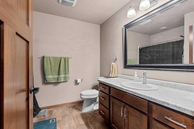 full bathroom with baseboards, visible vents, toilet, wood finished floors, and vanity