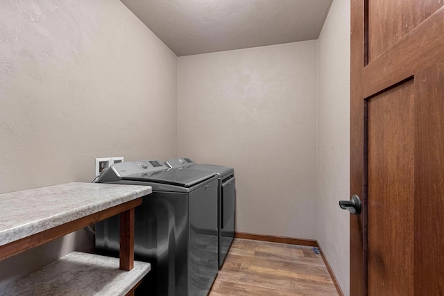 laundry area featuring light wood-type flooring, laundry area, baseboards, and washing machine and clothes dryer