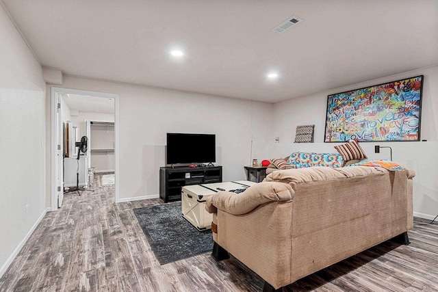 living room featuring baseboards, visible vents, wood finished floors, and recessed lighting