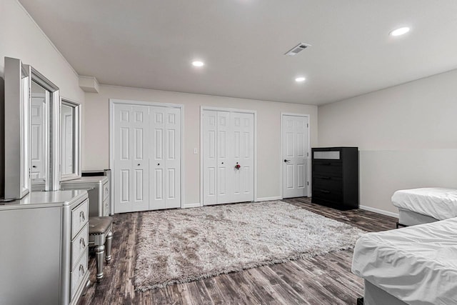 bedroom with dark wood finished floors, two closets, visible vents, and recessed lighting