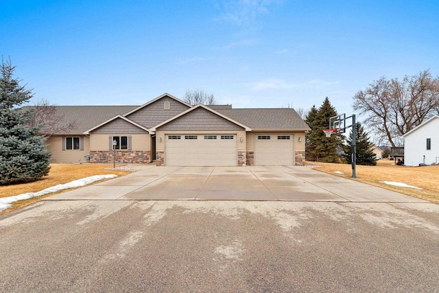 view of front of property featuring an attached garage, stone siding, and concrete driveway