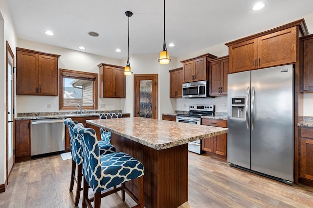 kitchen featuring appliances with stainless steel finishes, light wood-type flooring, a kitchen island, and a kitchen breakfast bar