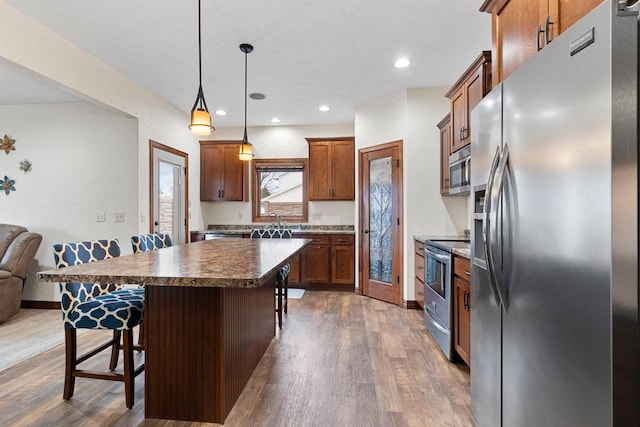 kitchen featuring stainless steel appliances, dark wood-type flooring, a kitchen breakfast bar, open floor plan, and a center island