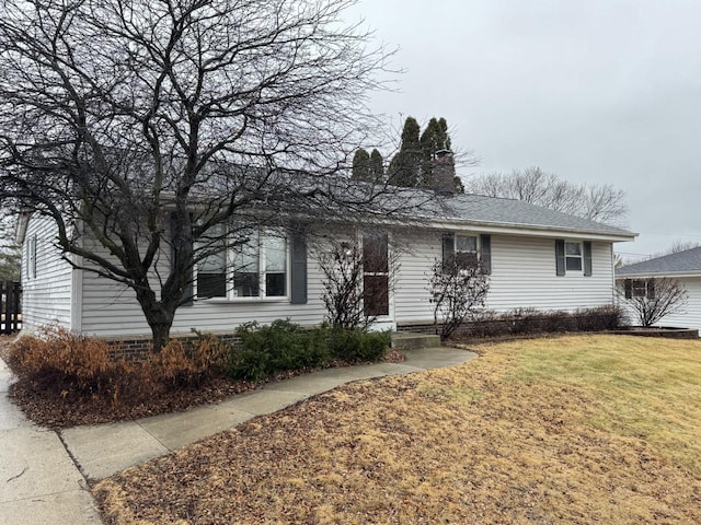 ranch-style house featuring a chimney and a front lawn