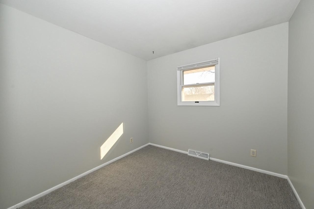 spare room featuring dark colored carpet, visible vents, and baseboards