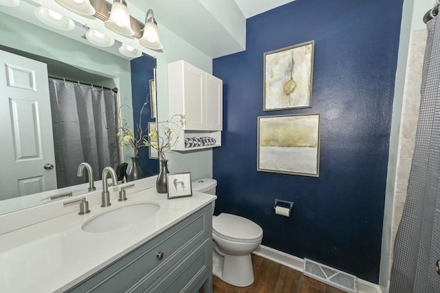 full bath with visible vents, toilet, wood finished floors, baseboards, and vanity