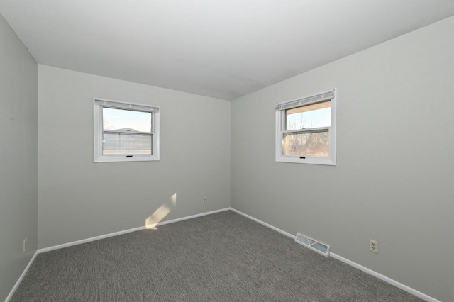 unfurnished room featuring baseboards, visible vents, and dark colored carpet