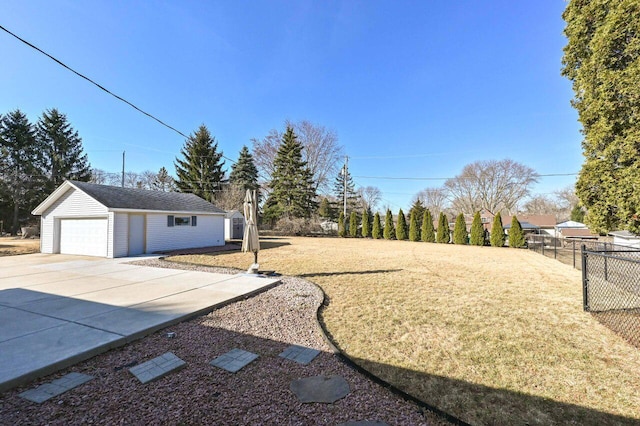 view of yard with a garage, an outdoor structure, driveway, and fence