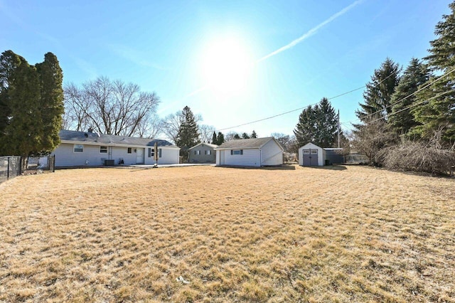 view of yard featuring an outbuilding, a storage unit, and fence