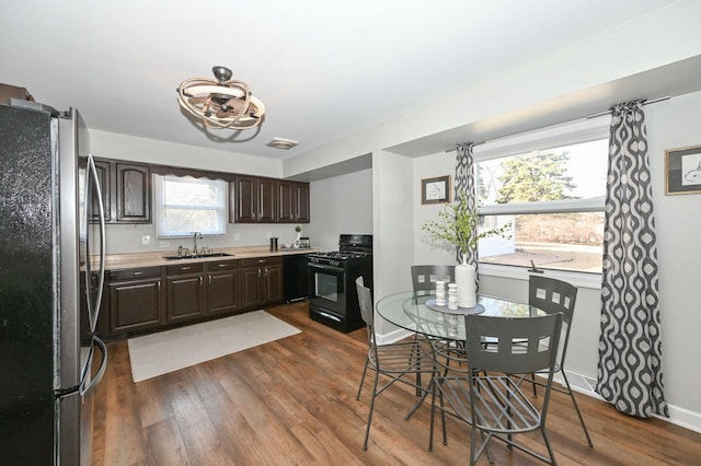 kitchen featuring gas stove, dark wood finished floors, freestanding refrigerator, light countertops, and dark brown cabinets