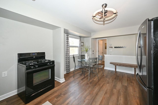 kitchen featuring black range with gas stovetop, baseboards, dark wood-style flooring, and freestanding refrigerator