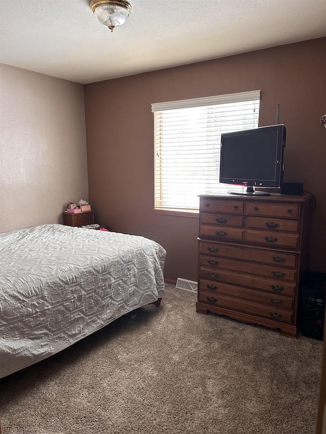 carpeted bedroom featuring multiple windows and a textured ceiling