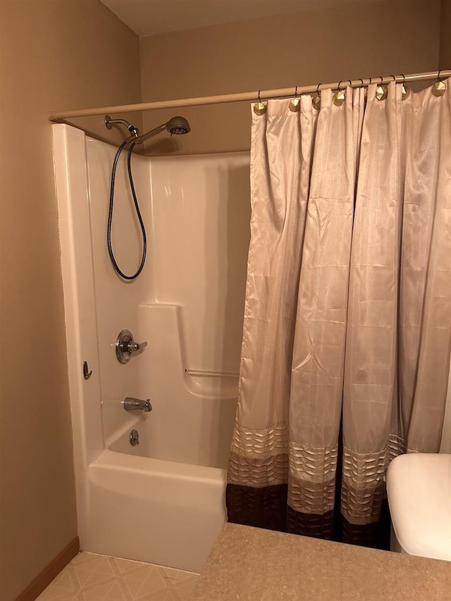 bathroom featuring baseboards, toilet, and shower / bathtub combination with curtain