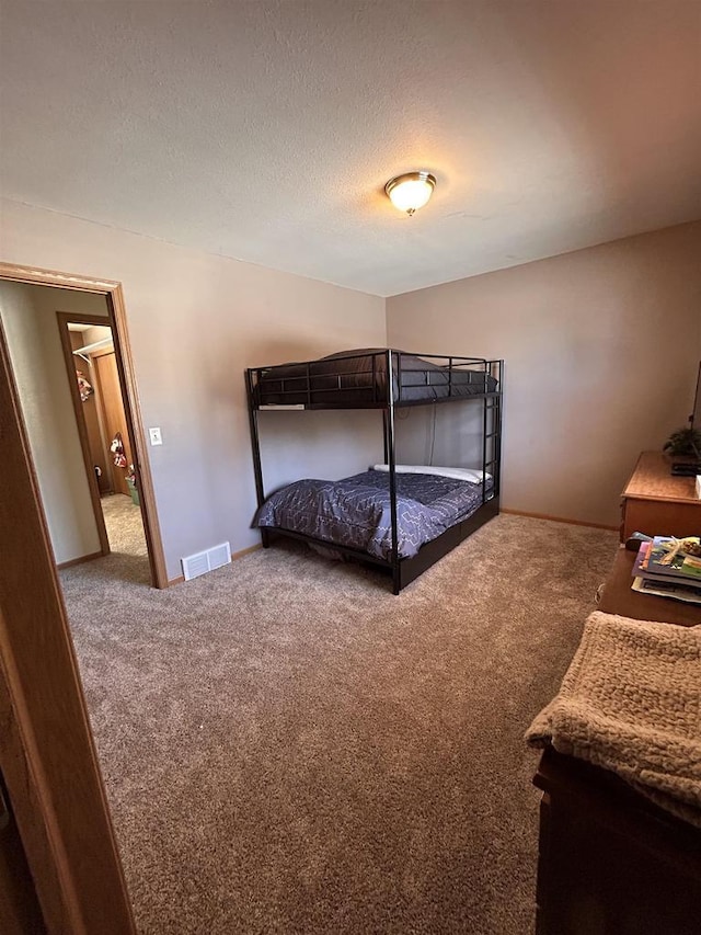 carpeted bedroom with visible vents, a textured ceiling, and baseboards