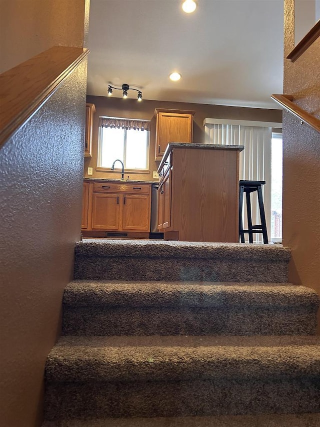 staircase featuring a textured wall and recessed lighting