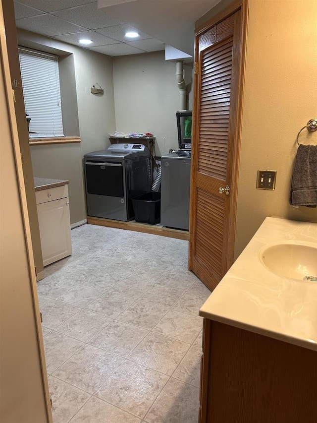 bathroom with a drop ceiling, a sink, and independent washer and dryer