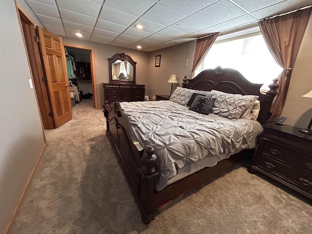 bedroom with a paneled ceiling, recessed lighting, a spacious closet, light carpet, and baseboards