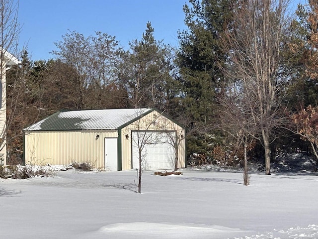 snow covered garage featuring a detached garage