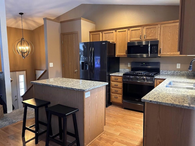 kitchen featuring lofted ceiling, black appliances, light wood finished floors, and a sink