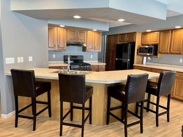 kitchen with light wood finished floors, light countertops, appliances with stainless steel finishes, and under cabinet range hood