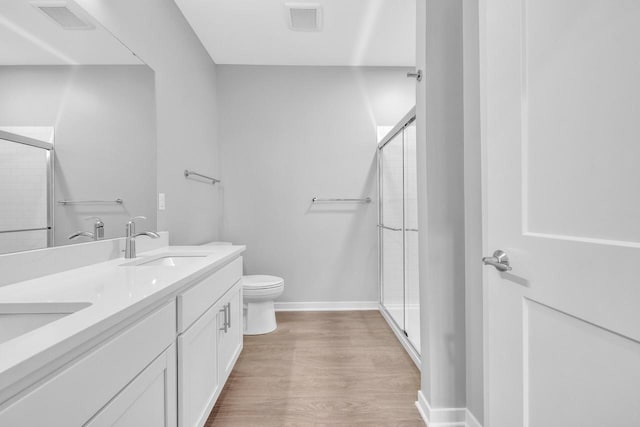 bathroom featuring visible vents, wood finished floors, a sink, and a shower with shower door