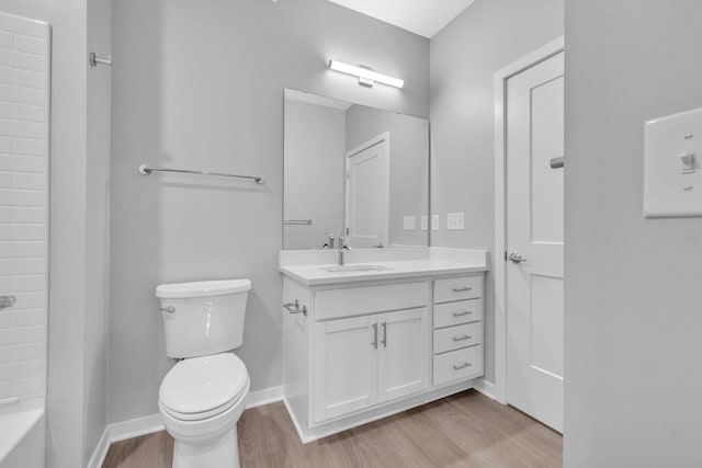 full bath with toilet, baseboards, wood finished floors, and vanity