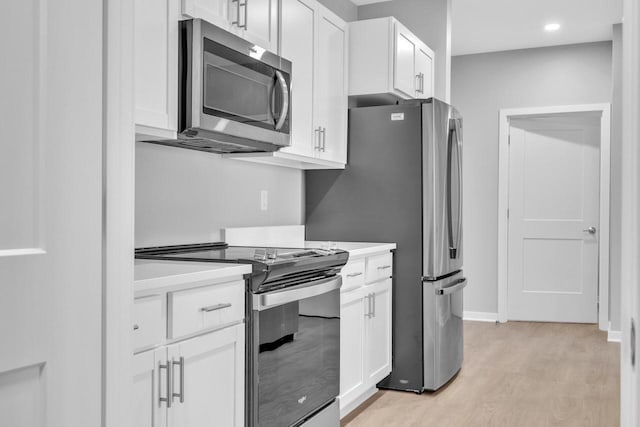 kitchen featuring stainless steel appliances, light countertops, light wood-style floors, and white cabinetry