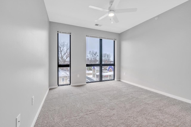 carpeted spare room with visible vents, ceiling fan, and baseboards