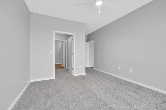 unfurnished bedroom featuring carpet flooring, ceiling fan, a spacious closet, and baseboards