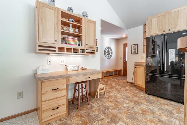 kitchen featuring light brown cabinets, baseboards, vaulted ceiling, open shelves, and black refrigerator with ice dispenser