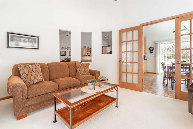 living area featuring light carpet, baseboards, and french doors