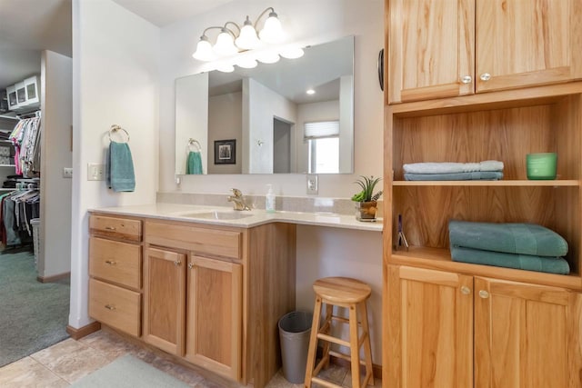 bathroom with a walk in closet, vanity, and tile patterned floors