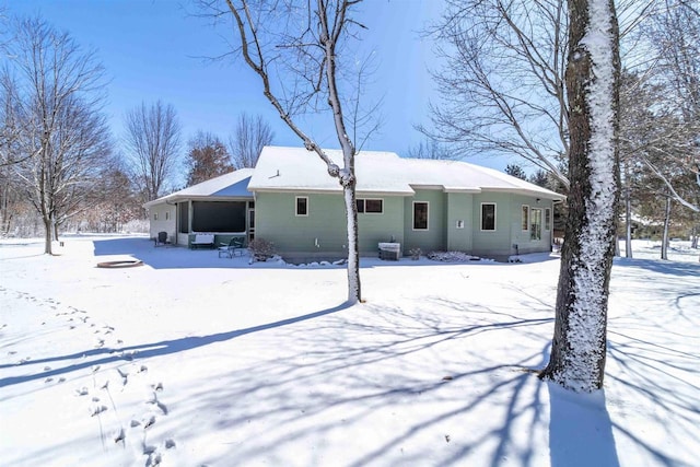 snow covered house featuring a garage and a sunroom