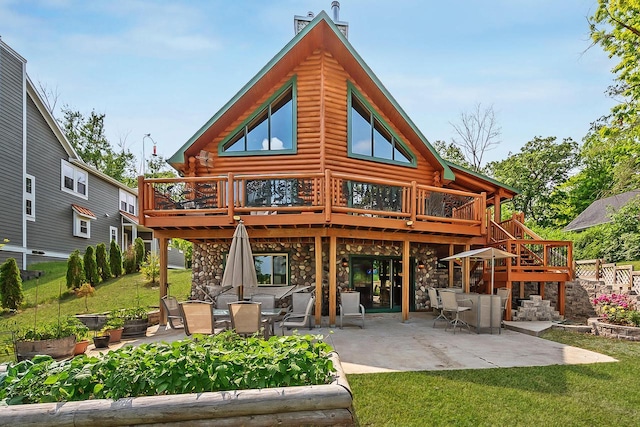 back of property with a lawn, log exterior, stone siding, a wooden deck, and a patio area