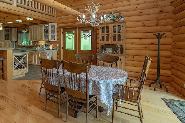 dining area with a chandelier, log walls, and light wood-style floors