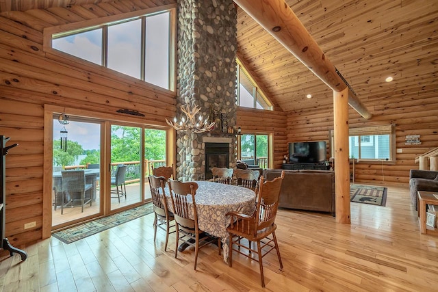 dining space with a fireplace, log walls, wood ceiling, light wood-type flooring, and beamed ceiling