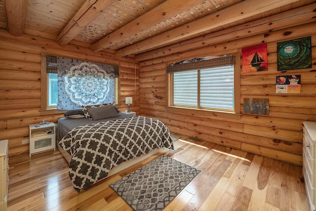 bedroom featuring rustic walls, light wood-style floors, and beamed ceiling