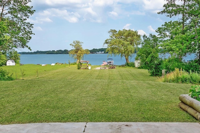 view of yard featuring a storage unit, an outdoor structure, and a water view