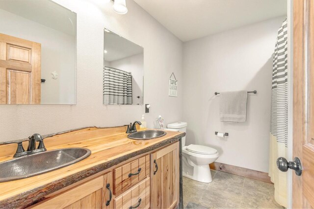 W5611 32nd St, New Lisbon, WI 53950 - bathroom with toilet, double vanity, a sink, and tile patterned floors