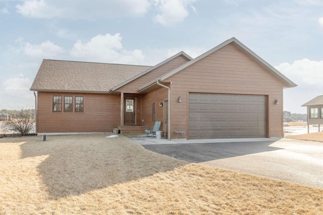 view of front of house featuring an attached garage, driveway, and roof with shingles