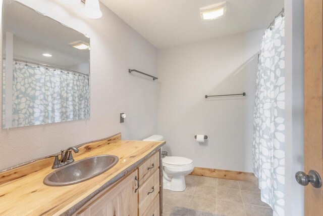 W5611 32nd St, New Lisbon, WI 53950 - full bath with a shower with shower curtain, toilet, vanity, baseboards, and tile patterned floors